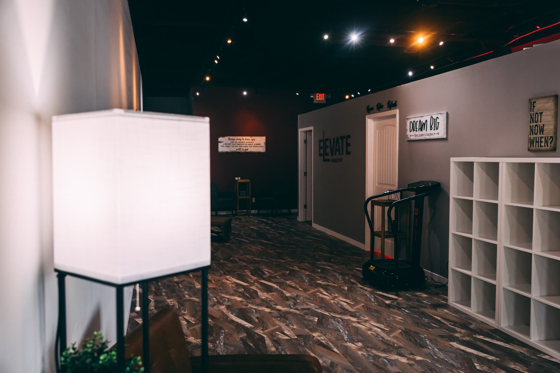 Warm studio lounge with a soft lamp glow and the ELEVATE wall logo