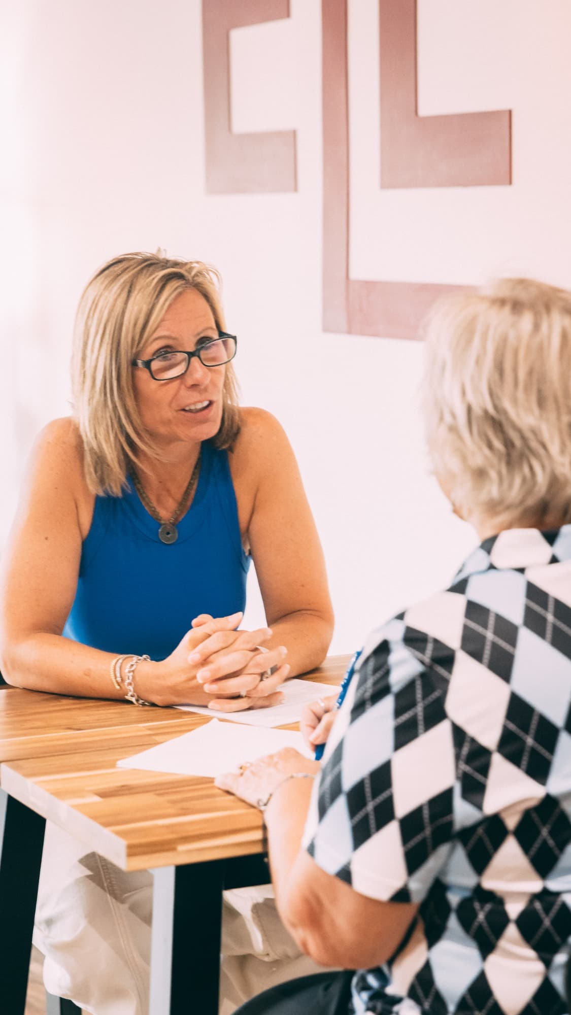 Elevate founder Jaime Hughes smiling as she talks with a client across a table at the studio