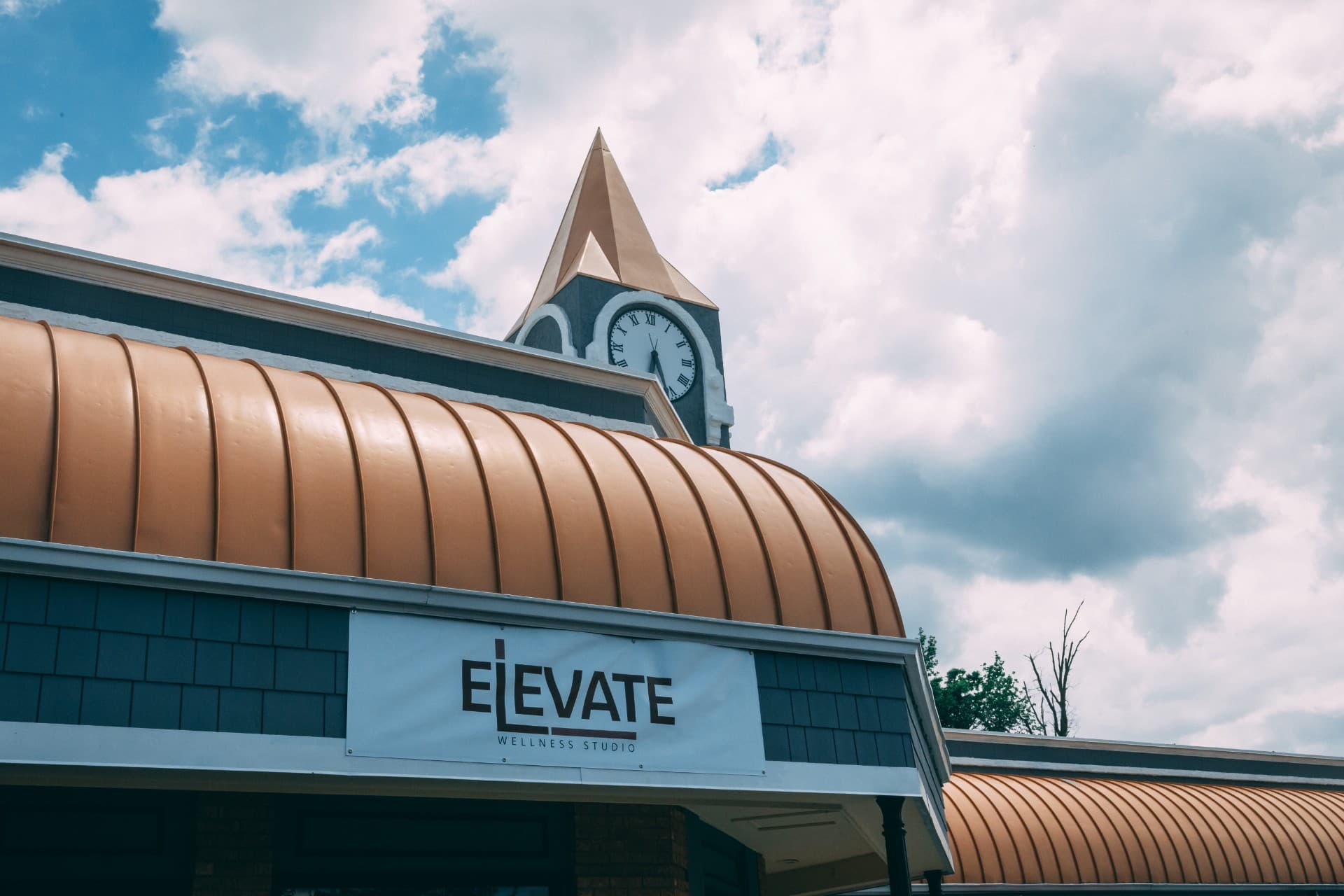 Exterior of Elevate Wellness Studio — the brick building with its signature clock tower and ELEVATE sign against a bright blue sky